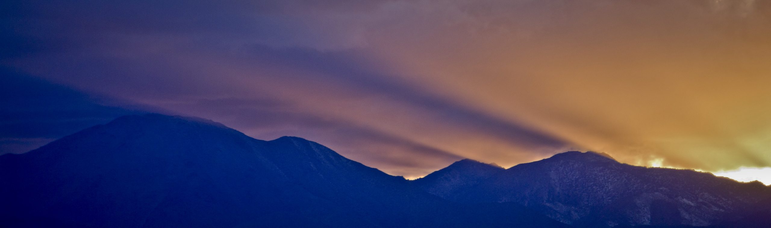 a sunset behind silhouetted mountains